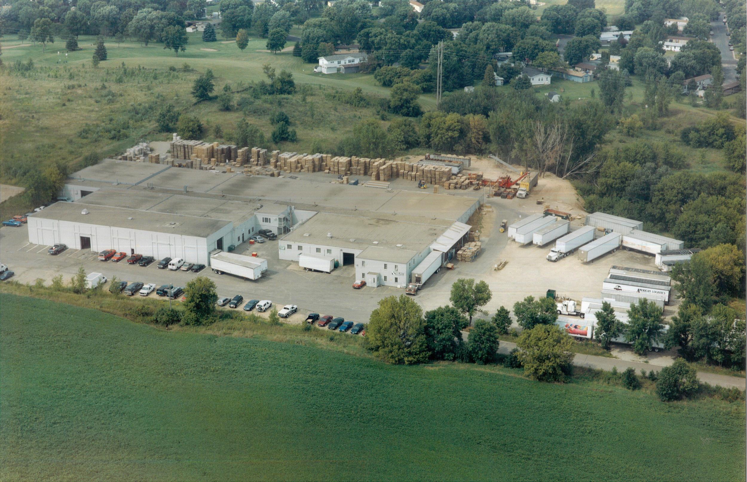 Aerial view of the Gruber Pallets yard in Lake Elmo, Minnesota, with rows of stacked pallets, the mill buildings and trailers parked along the lot.