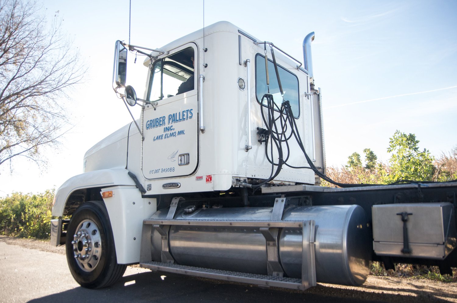 A white Gruber Pallets tractor unit with the company name on the door, ready to pull a load out of the Lake Elmo yard.