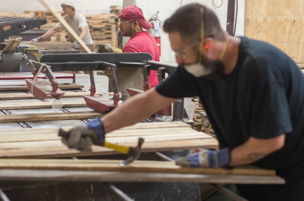 Crew repairing used pallet boards on a recycling line